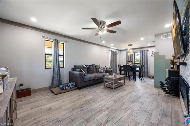 Living area featuring ceiling fan, light wood-style flooring, crown molding, and recessed lighting