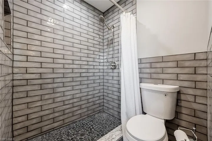 Full bath featuring a shower stall and toilet