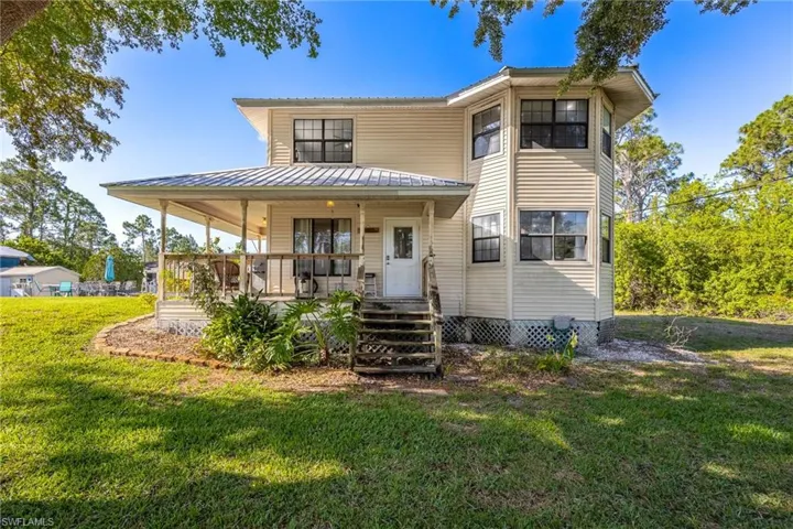 View of front of property with covered porch, a front lawn, and metal roof