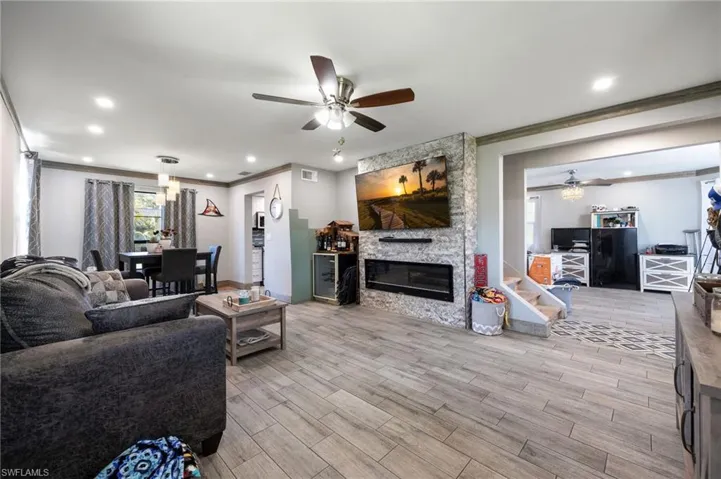 Living room with ceiling fan, crown molding, wood finished floors, a fireplace, and recessed lighting
