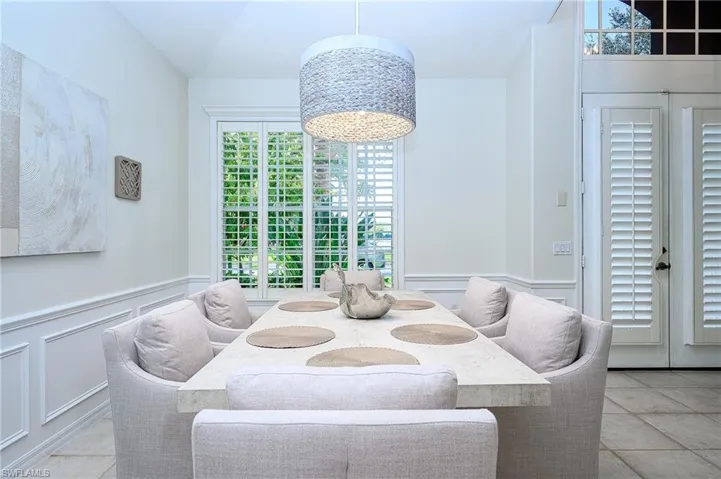 Tiled dining area featuring lofted ceiling and a notable chandelier