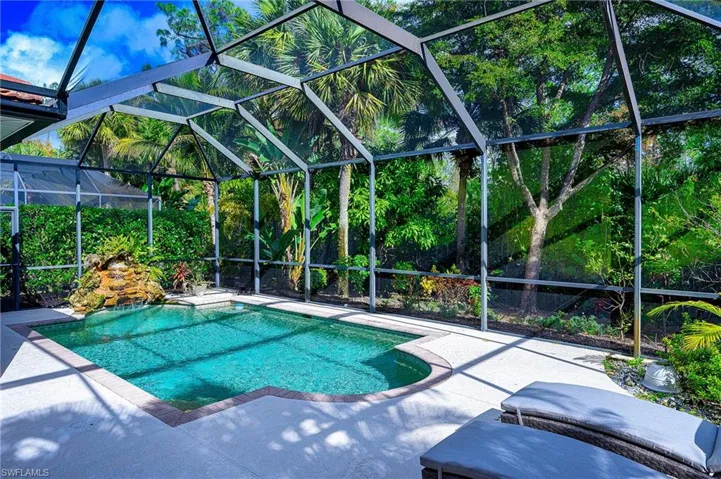View of pool with glass enclosure and a patio