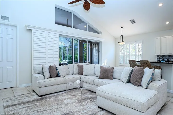 Living room with high vaulted ceiling, light tile patterned floors, and ceiling fan