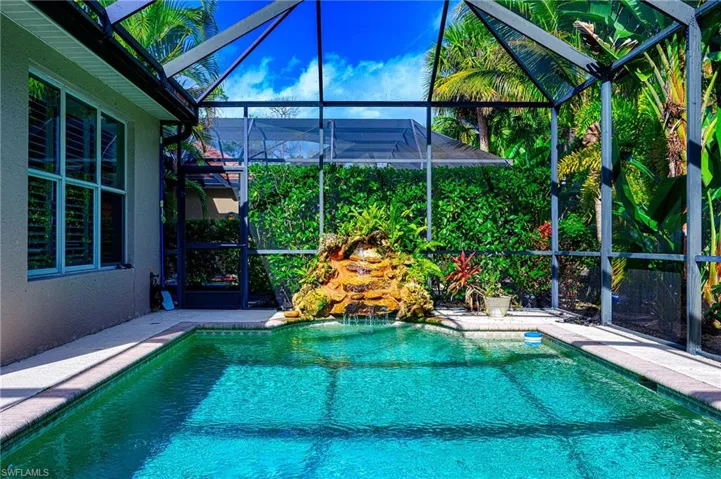 View of swimming pool with glass enclosure and a patio area