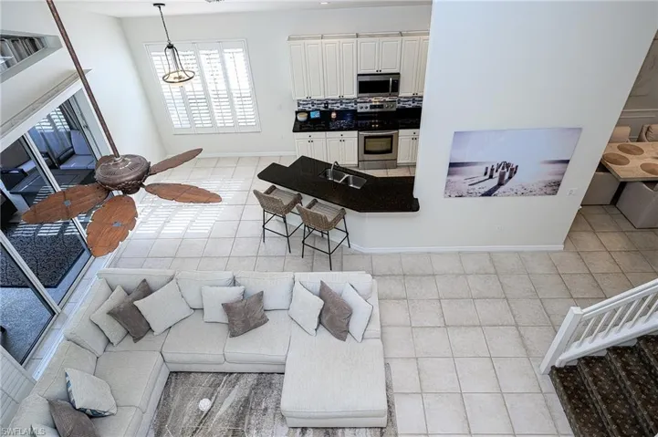 Tiled living room featuring sink and ceiling fan with notable chandelier