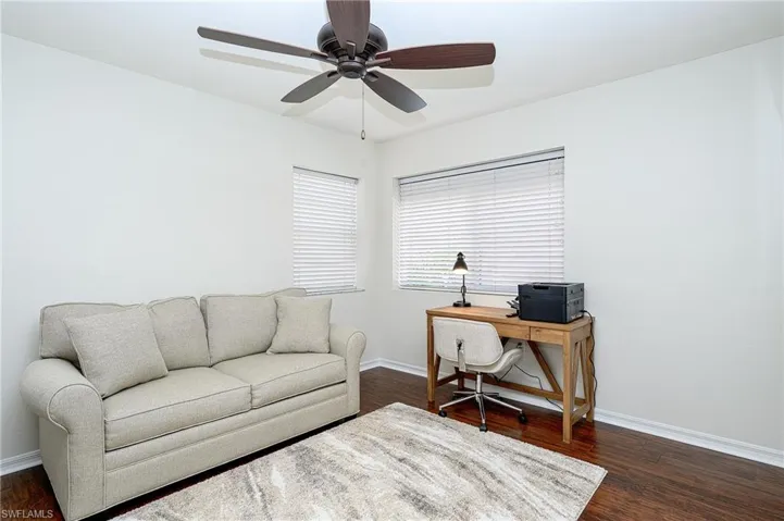 Office with dark hardwood / wood-style flooring and ceiling fan
