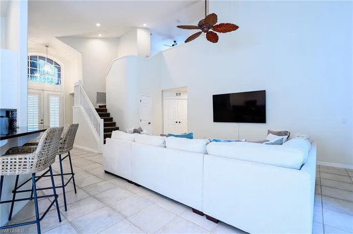 Living room featuring light tile patterned floors, ceiling fan, and a towering ceiling