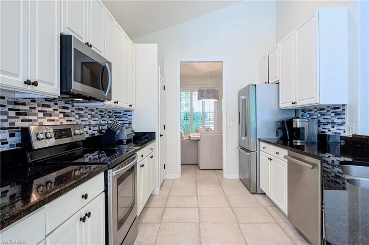 Kitchen featuring white cabinets, stainless steel appliances, and dark stone countertops