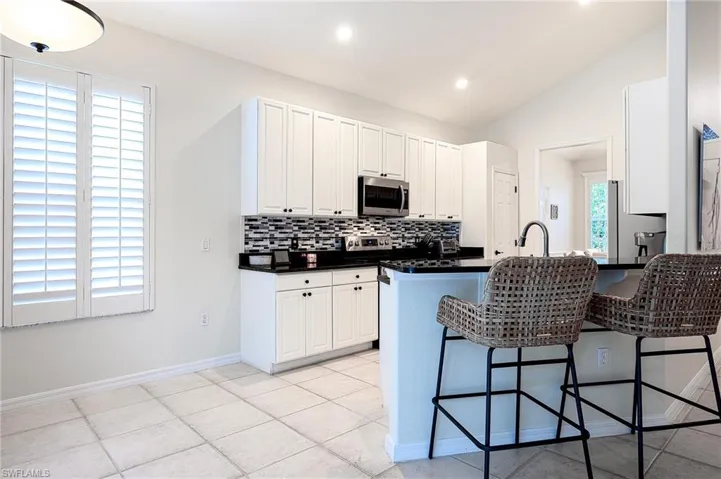 Kitchen featuring appliances with stainless steel finishes, vaulted ceiling, a healthy amount of sunlight, white cabinets, and kitchen peninsula