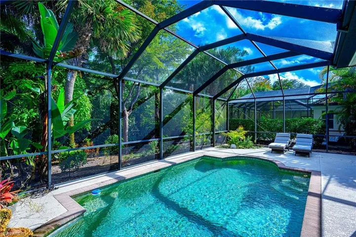 View of pool with glass enclosure and a patio