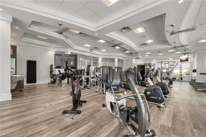 Gym with ceiling fan, crown molding, and light hardwood / wood-style flooring