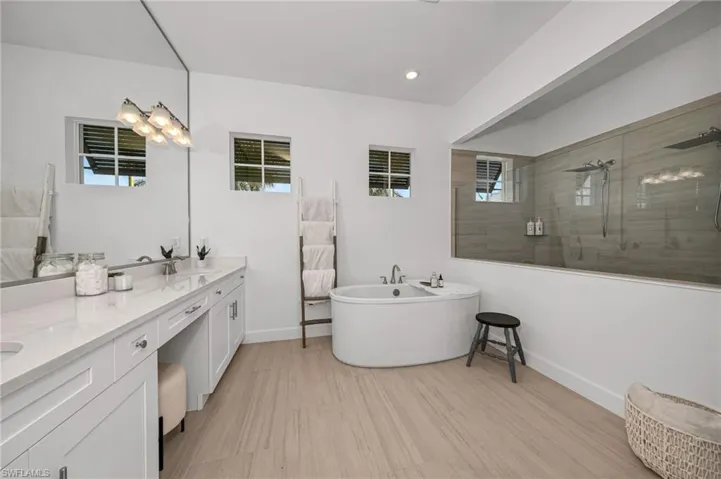 Bathroom featuring dual custom mirror vanity and twin waterfall showers