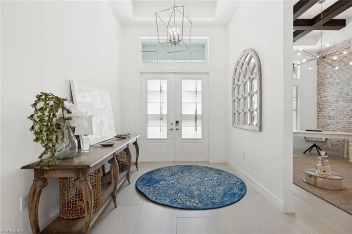Tiled foyer entrance with a chandelier, french doors, and a raised ceiling
