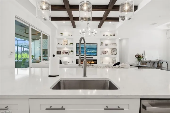 Kitchen with a chandelier, white cabinets, beamed ceiling, sink, and coffered ceiling