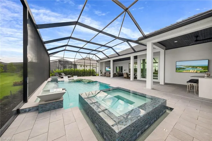 View of swimming pool featuring a patio area, pool water feature, ceiling fan, an in ground hot tub, and glass enclosure