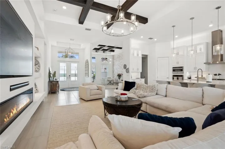 Living room featuring sink, a high ceiling, beam ceiling, light tile patterned flooring, and coffered ceiling