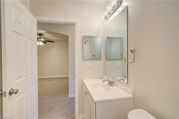 Bathroom with ceiling fan, vanity, and toilet