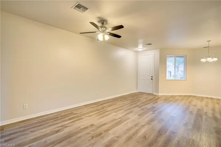 Spare room with hardwood / wood-style flooring and ceiling fan with notable chandelier