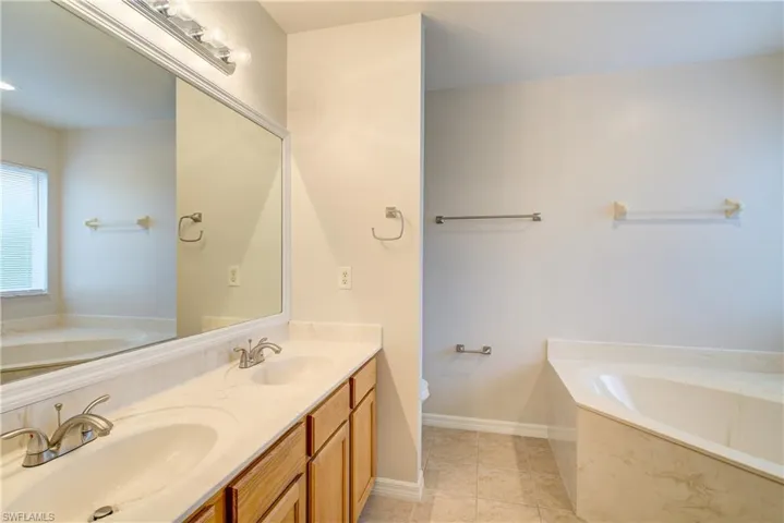 Bathroom featuring vanity, toilet, a bathing tub, and tile patterned flooring