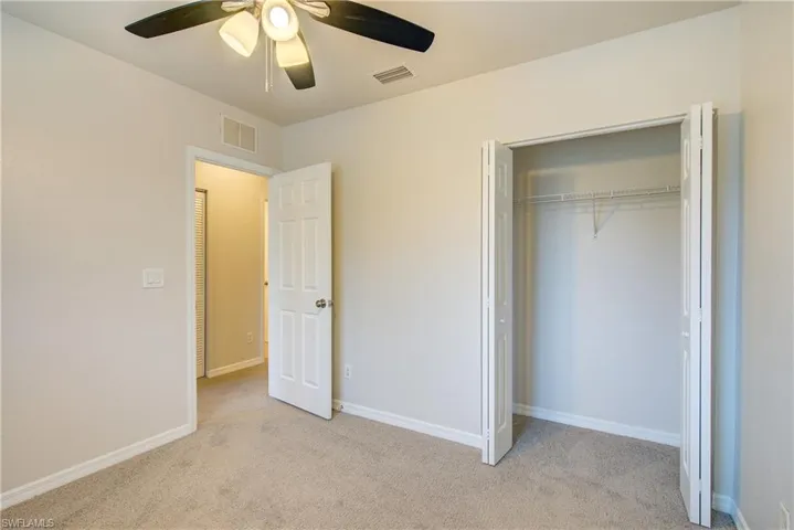 Unfurnished bedroom featuring ceiling fan, light colored carpet, and a closet