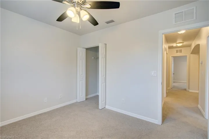Carpeted spare room featuring ceiling fan