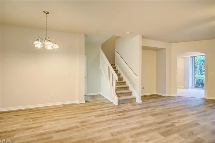 Spare room featuring an inviting chandelier and light hardwood / wood-style floors