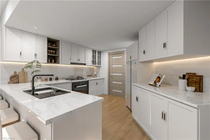 Kitchen with backsplash, open shelves, a peninsula, a breakfast bar area, and oven