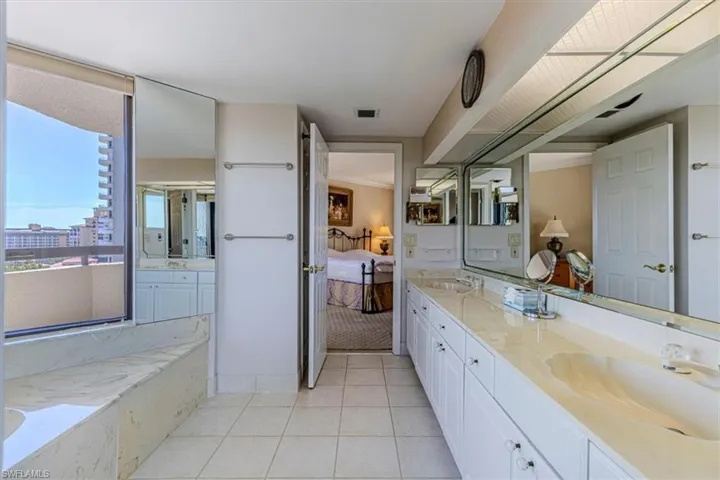 Bathroom featuring double vanity, ensuite bath, a garden tub, and light tile patterned floors