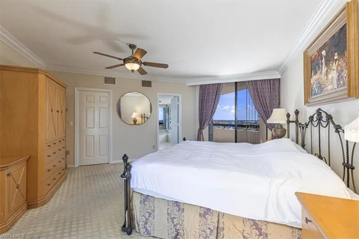 Bedroom featuring light colored carpet, ornamental molding, a ceiling fan, and ensuite bathroom