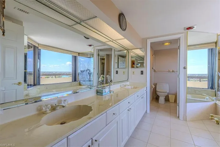 Bathroom featuring a bath, double vanity, and light tile patterned floors