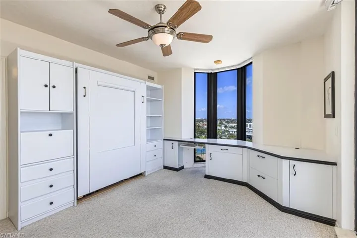 Unfurnished office with a ceiling fan and light carpet