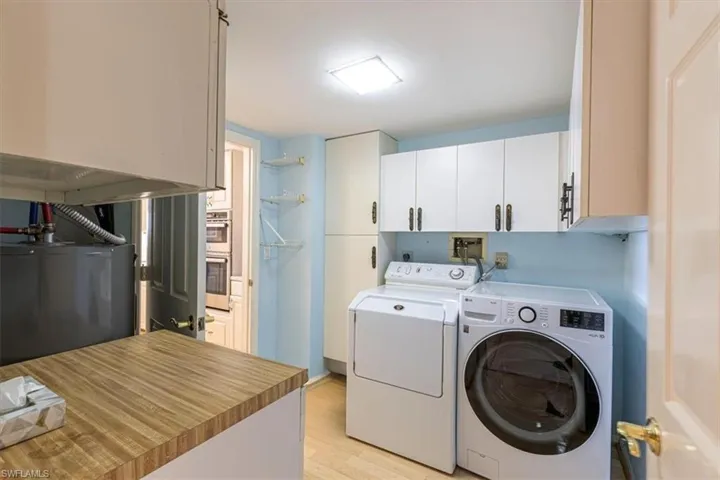 Laundry room with light wood finished floors, washing machine and clothes dryer, and cabinet space