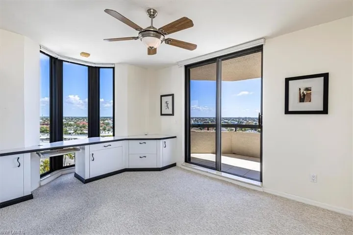 Unfurnished office featuring ceiling fan, light colored carpet, and floor to ceiling windows