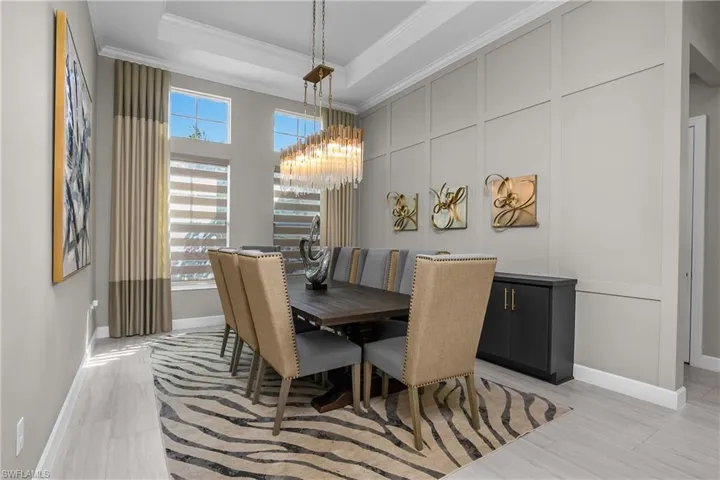 Dining room featuring suspended lighting, a decorative wall, crown molding, and a tray ceiling