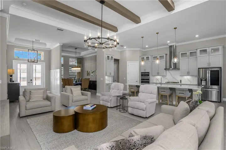 Living room featuring crown molding, hanging lights, wood finished floors, french doors, and a raised ceiling