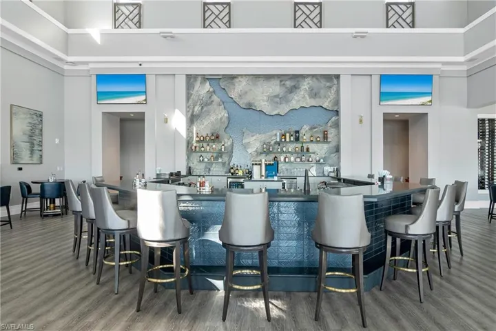 Bar with dark countertops, a high ceiling, and open shelves