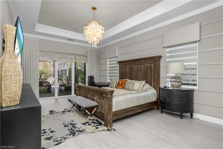Bedroom featuring access to exterior, suspended lighting, a tray ceiling, and ornamental molding