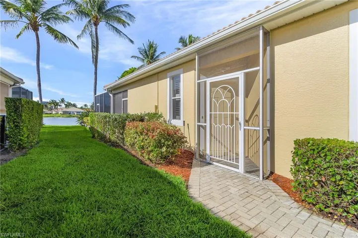 Doorway to property with stucco siding, a lawn, and a water view