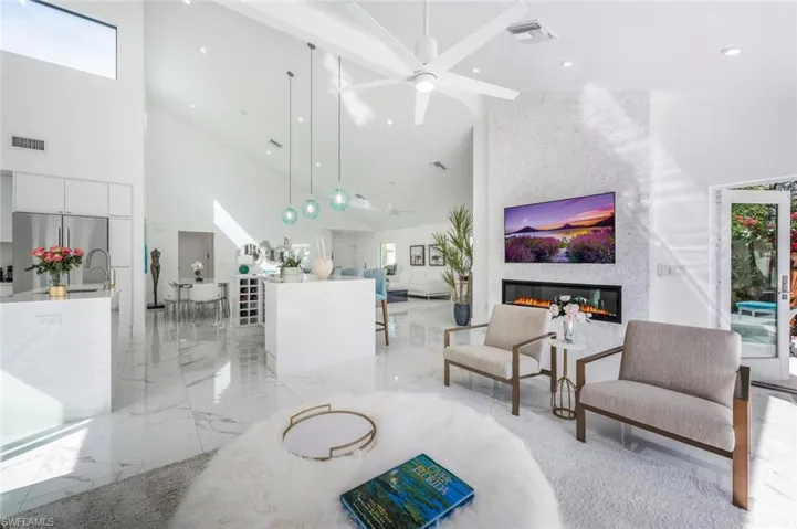Living room with high vaulted ceiling, sink, ceiling fan, and a fireplace