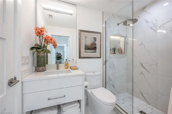 Bathroom featuring toilet, vanity, and tiled shower