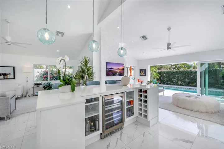 Kitchen featuring vaulted ceiling, pendant lighting, and wine cooler