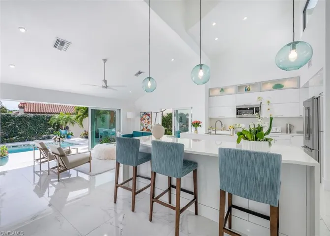 Kitchen with decorative light fixtures, white cabinetry, plenty of natural light, sink, and ceiling fan