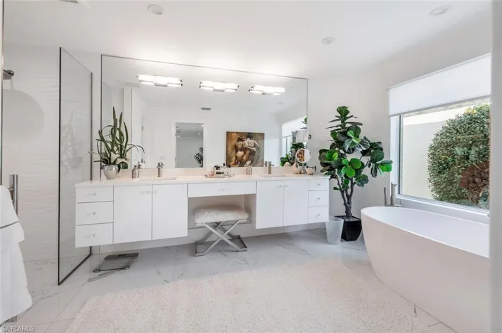 Bathroom featuring vanity, plenty of natural light, and a bath