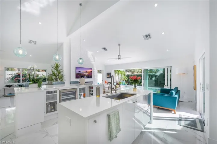 Kitchen with white cabinets, a kitchen island with sink, sink, and pendant lighting
