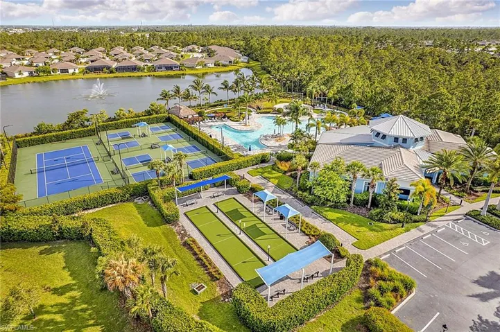 Expansive recreational area featuring multiple tennis and pickleball courts, two bocce ball courts, a large swimming pool, and a clubhouse building