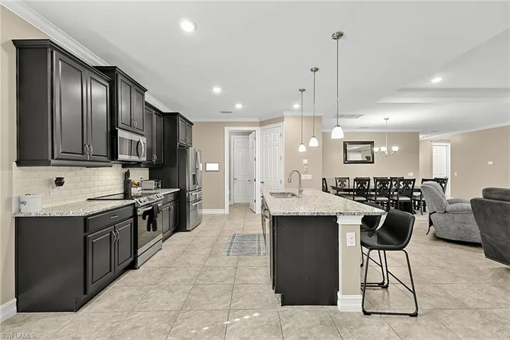 Kitchen featuring dark-finish cabinetry, stainless steel appliances, speckled countertops, and tile backsplash