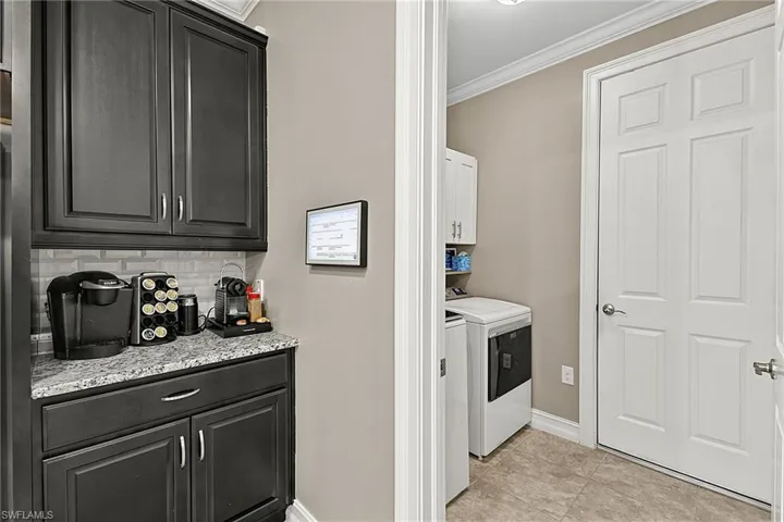 Black cabinetry with silver hardware, light granite countertop, and light subway tile backsplash