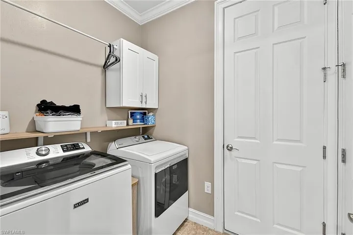 Dedicated laundry area featuring a light wood shelf, white upper cabinetry, and a clothes hanging rod