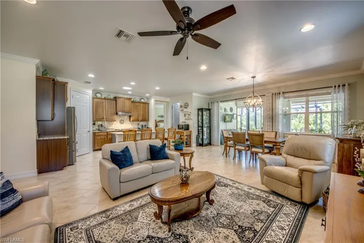 Tiled living room with ornamental molding and ceiling fan with notable chandelier