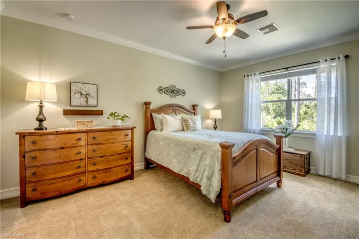 Carpeted bedroom with crown molding and ceiling fan